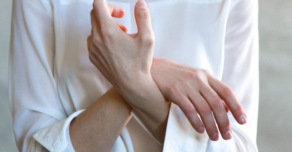 Elegant hands in a white shirt gently touching each other, symbolizing calm and tenderness via Pexels.