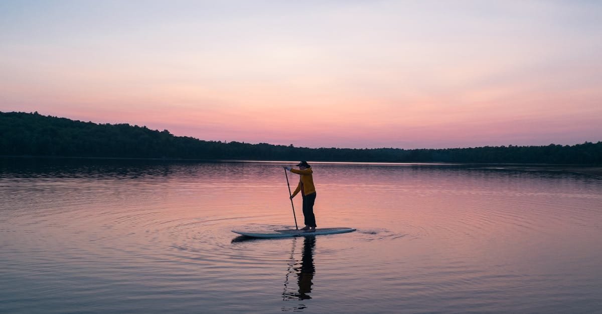 A serene scene of a person paddleboarding on a tranquil lake during sunset, reflecting golden hues via Pexels.