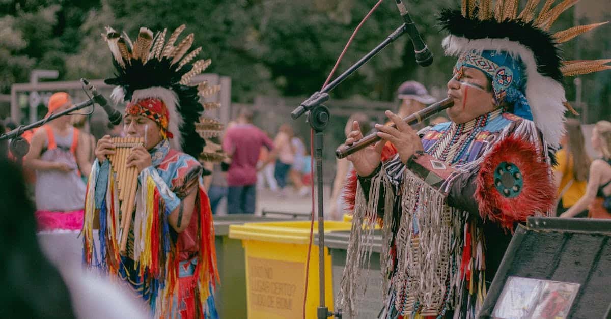 Native American musicians performing outdoors in traditional wear with woodwind instruments via Pexels.