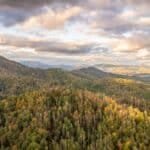 Scenic aerial view of Appalachian Mountains with autumn foliage under dramatic clouds.