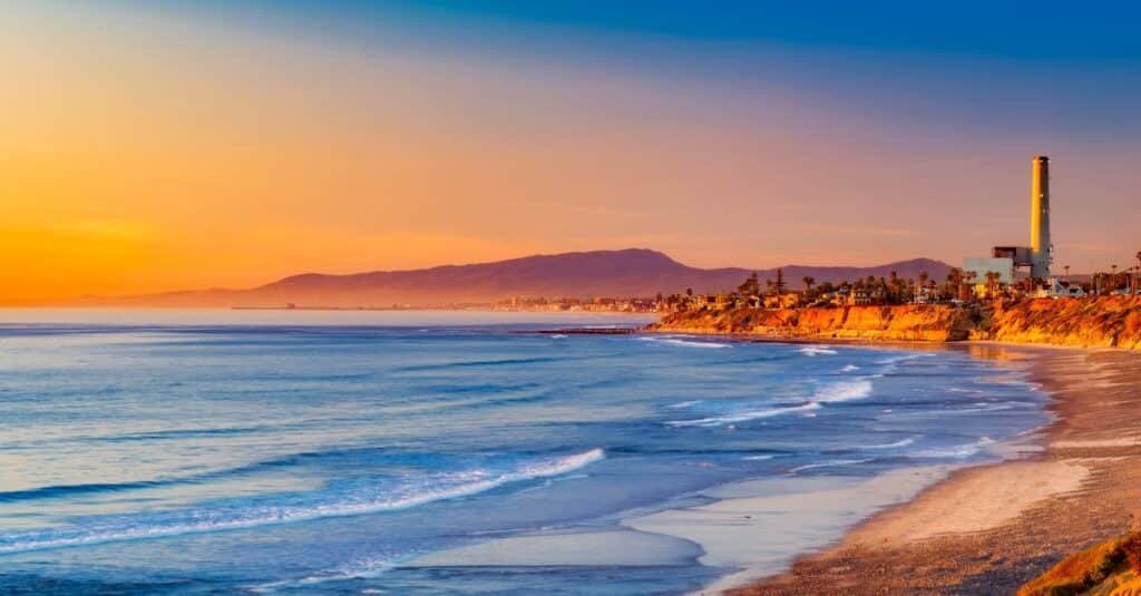 Golden sunset over a serene California coastline, with rolling waves meeting the sandy shore via Pexels.