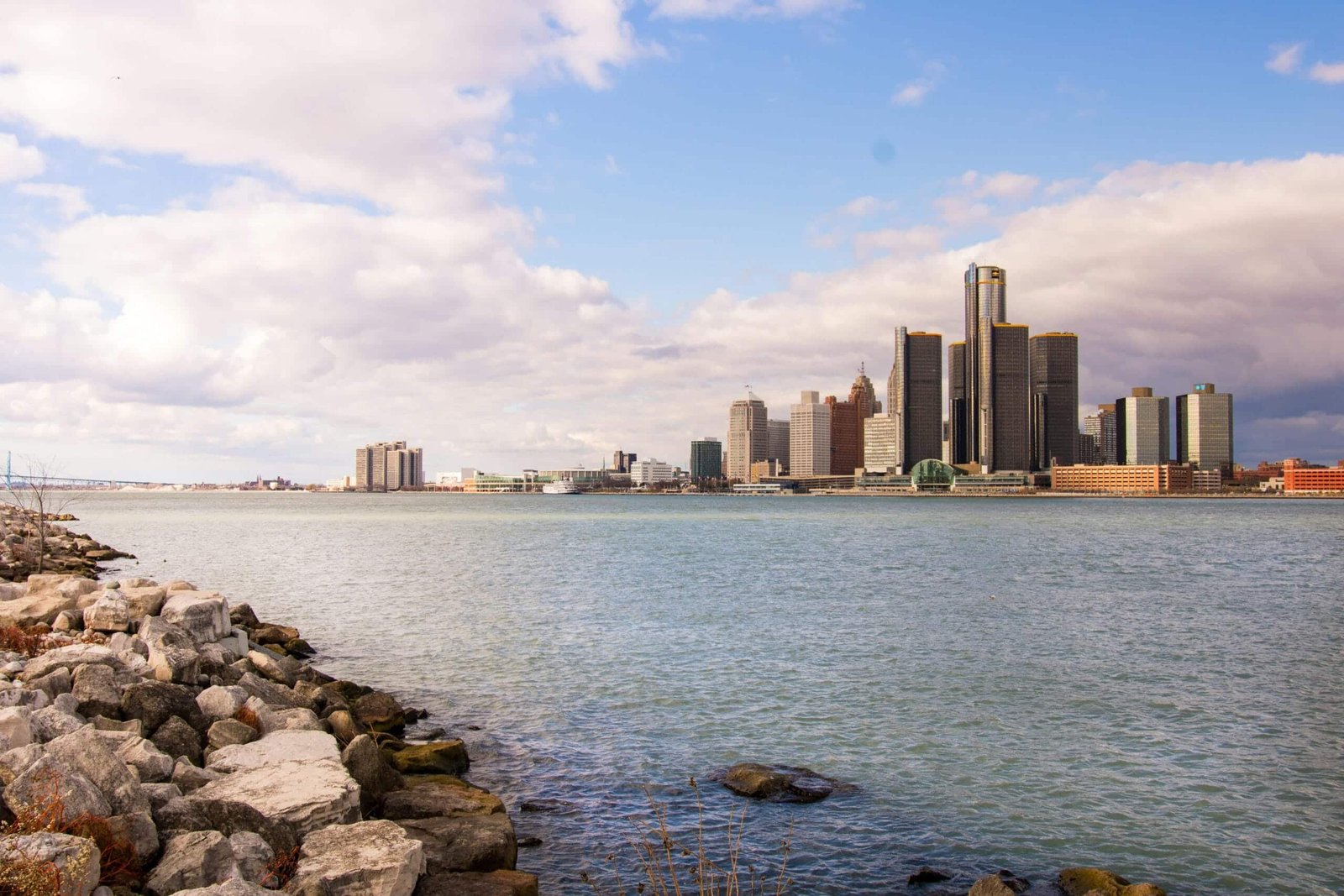 View of the Detroit skyline across the river on a clear day with rock-strewn waterfront via Pexels