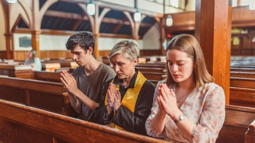 Adults praying together in a serene church interior, fostering religious devotion. via Pexels