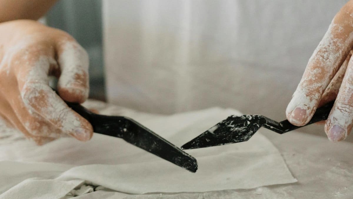 Close-up of an artisan shaping clay with precision tools, showcasing the art of pottery.
