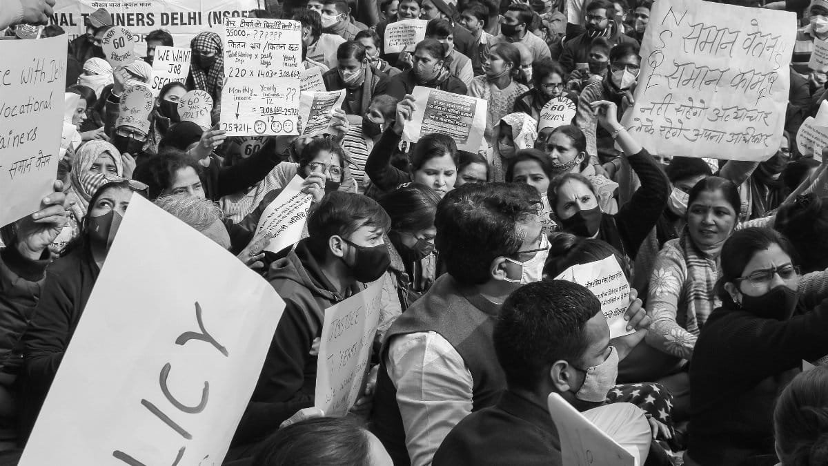 Black and white image of a crowded protest rally in Delhi advocating for policy reform.