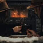 A couple enjoying wine by the fireplace, embracing romance and warmth. via Pexels