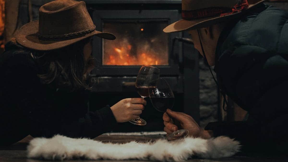 A couple enjoying wine by the fireplace, embracing romance and warmth. via Pexels