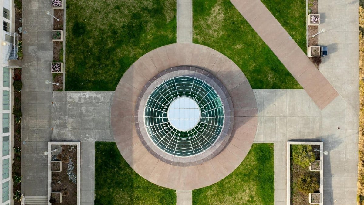 Drone shot of a circular glass ceiling and pathways on a university campus.