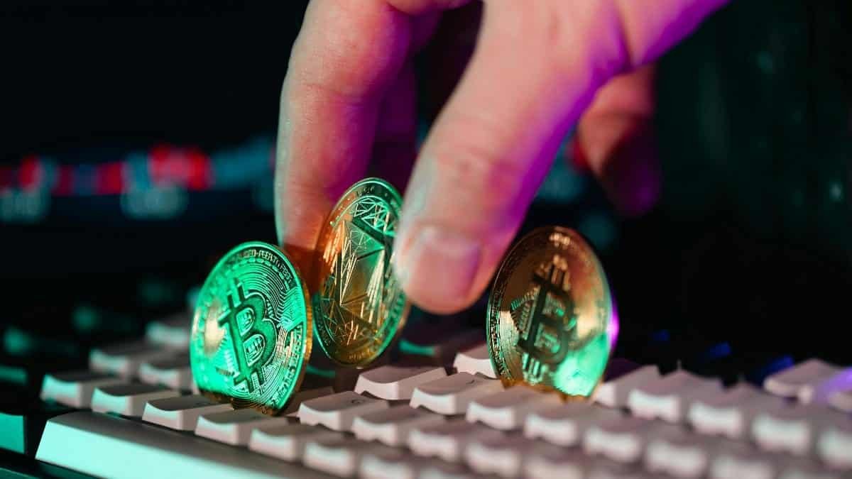 Close-up of cryptocurrency coins on a keyboard with a hand, symbolizing digital currency and finance technology.