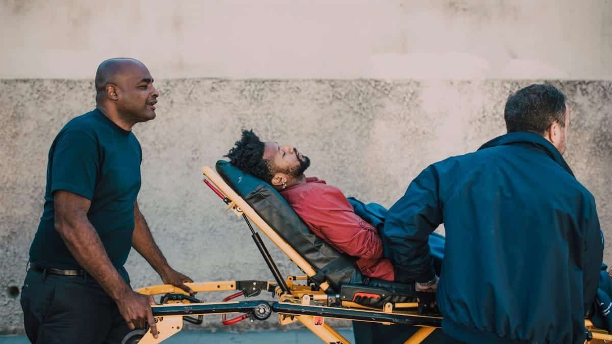 Two paramedics assist an unconscious patient on a stretcher outside. Medical emergency care concept.
