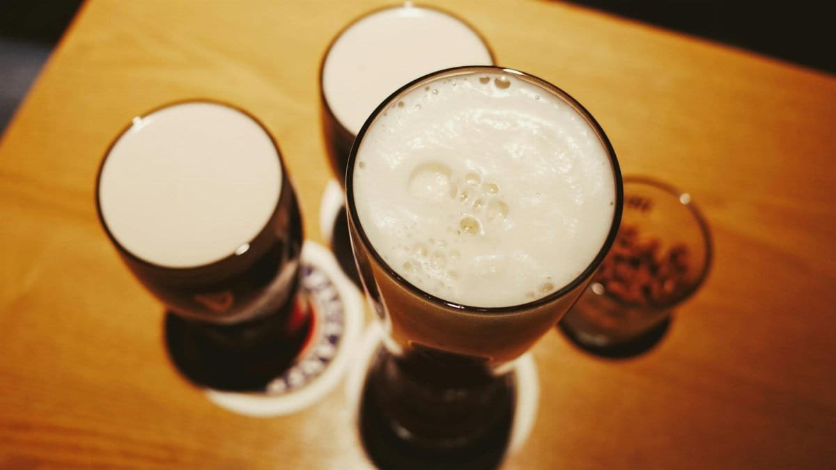 A high-angle shot of glasses of beer with rich foam on a wooden table, creating a cozy and inviting atmosphere.