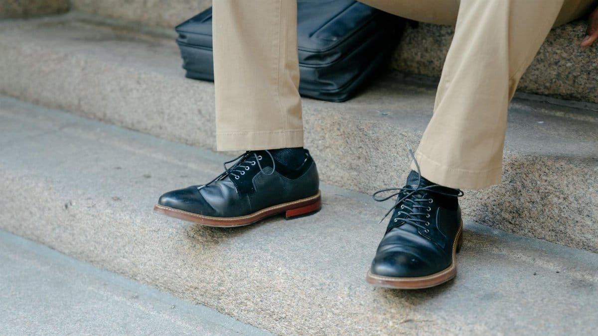 Close-up of elegant black leather shoes paired with khaki pants on outdoor steps.