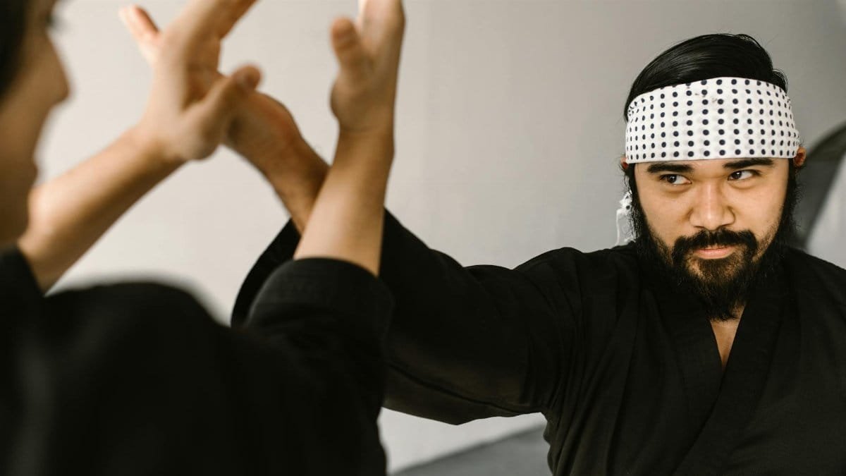 Bearded martial artist practicing self-defense with focus and precision indoors.
