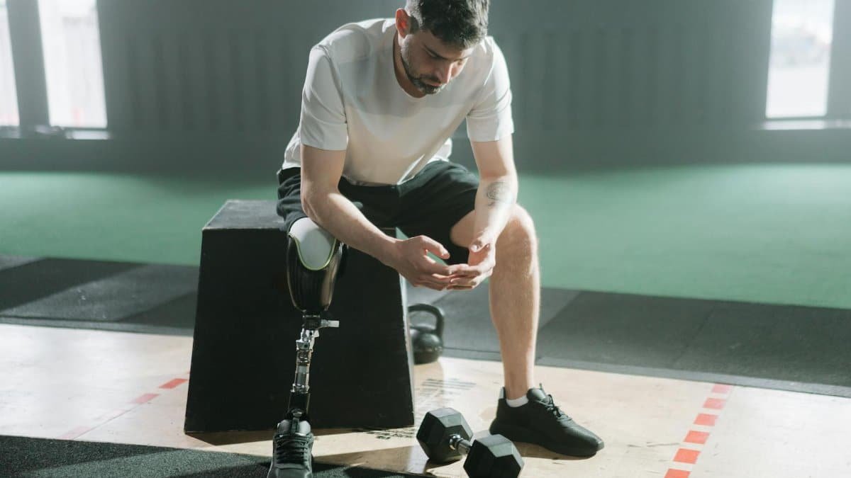 Inspirational portrait of a male athlete with a prosthetic leg sitting in a gym, embracing the challenge of fitness.