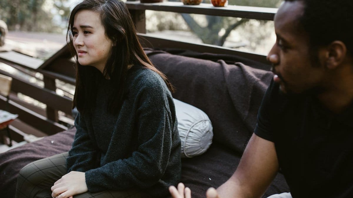 A man and woman having an emotional discussion on an outdoor bench.