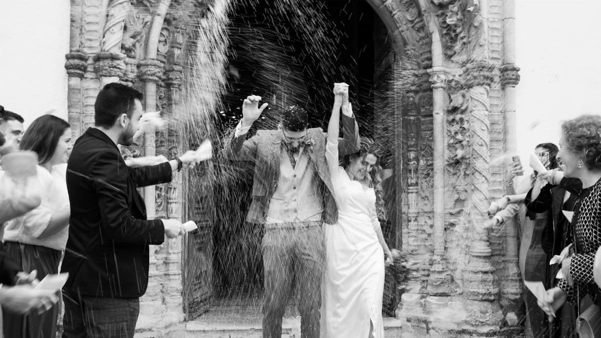 A joyful bride and groom celebrate with guests outside a historic church