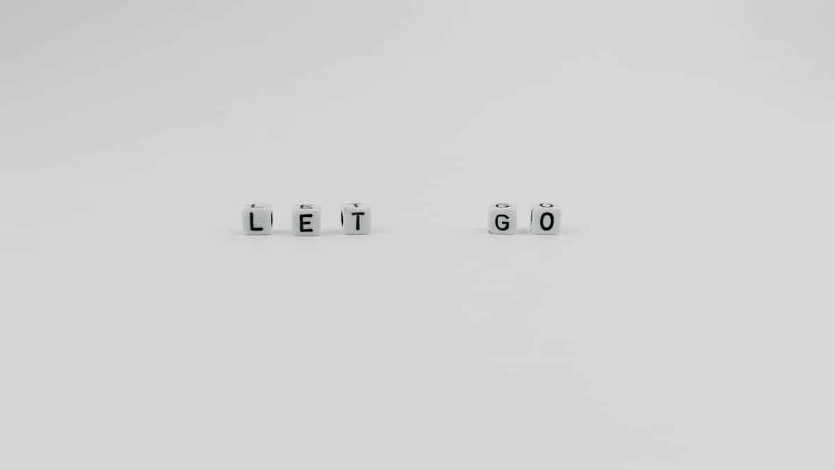 Simple white dice spelling 'LET GO' on a plain surface, conveying inspiration and motivation.