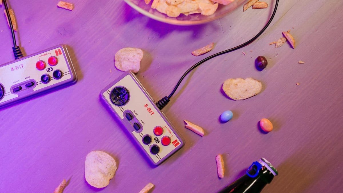 Vintage game controllers and snacks on a table create a nostalgic gaming vibe.
