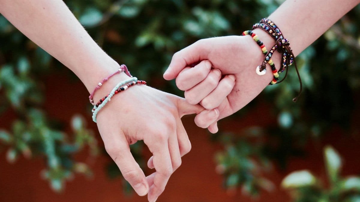 Two hands with colorful bracelets interlocked, symbolizing friendship and connection.