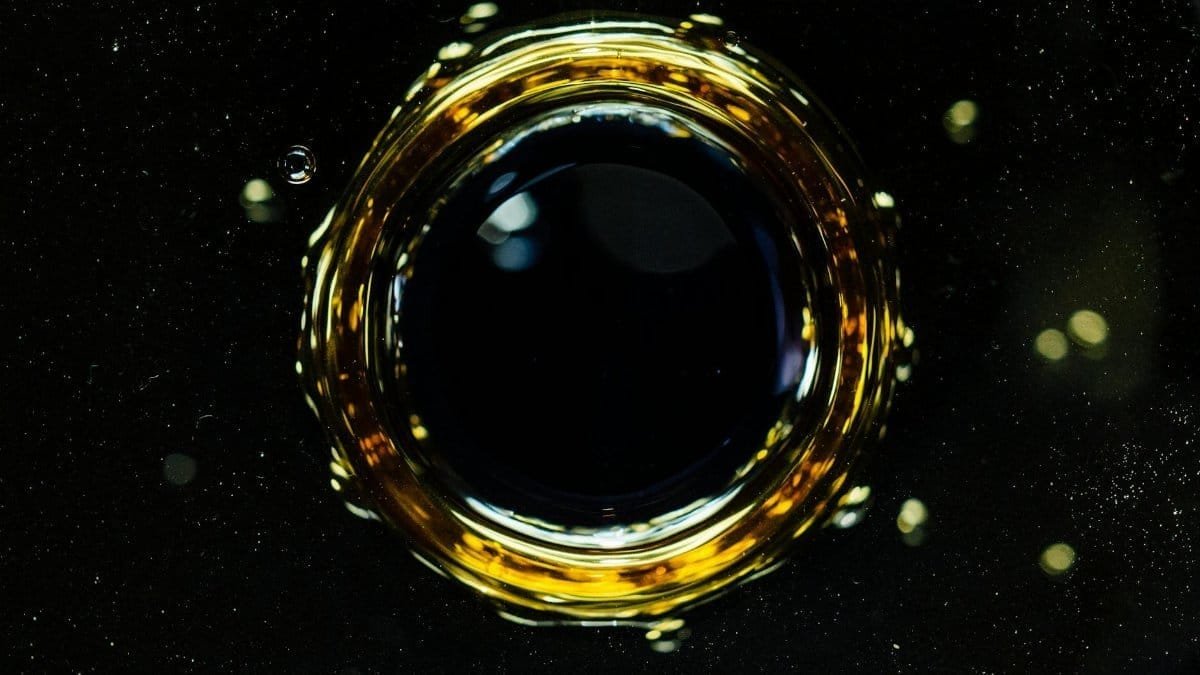 Background of macro drop falling into dark liquid and forming circle and bubbles on surface