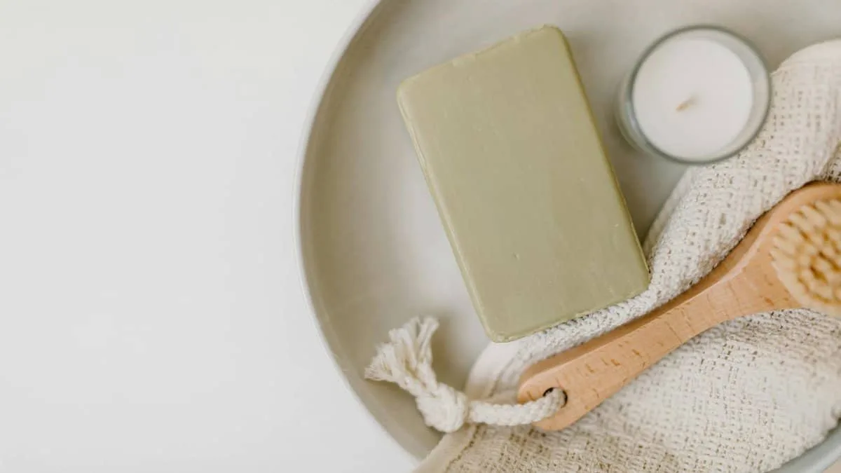 A flat lay of soap, candle, brush, and cloth for a calming self-care routine.