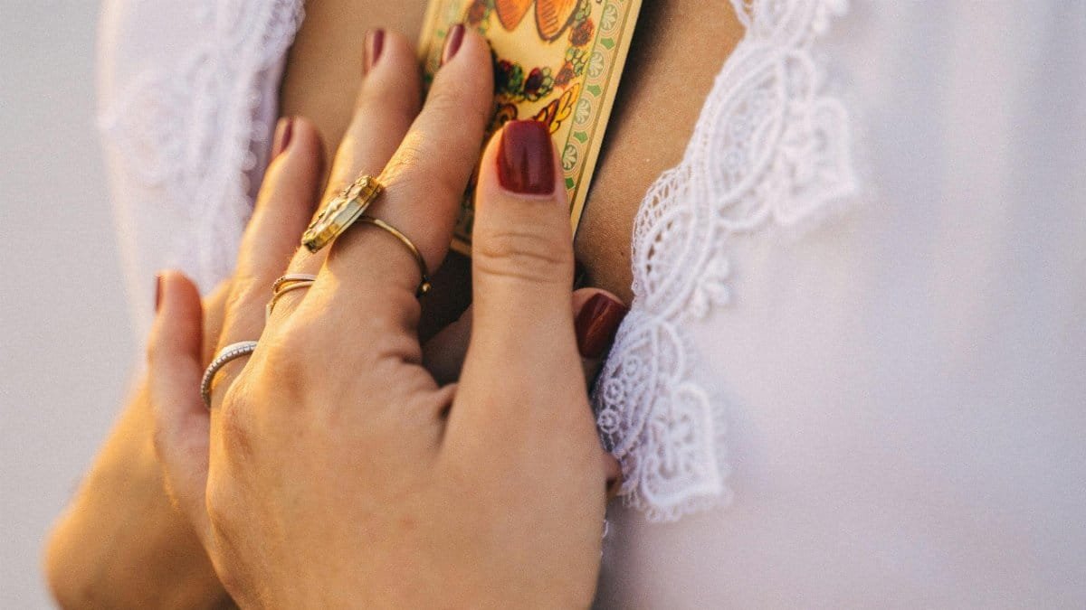 Close-up of a woman's hands holding a tarot card near her heart, showcasing elegance and spirituality.