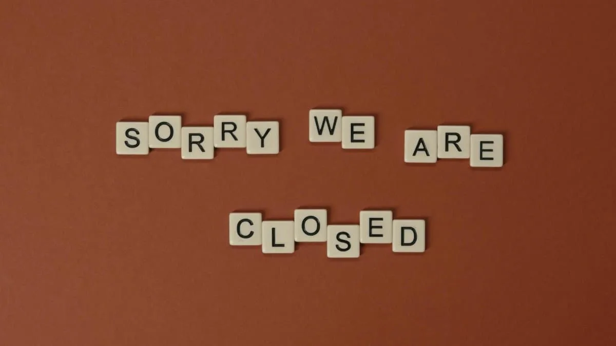 Scrabble tiles on a brown surface forming the phrase 'Sorry We Are Closed' with copy space.