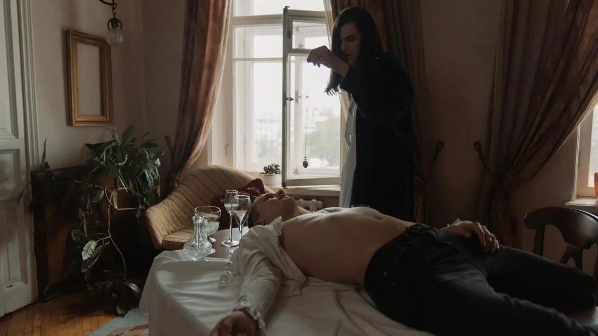 A mysterious androgynous figure performs a ritual in a vintage room, creating a dramatic atmosphere.