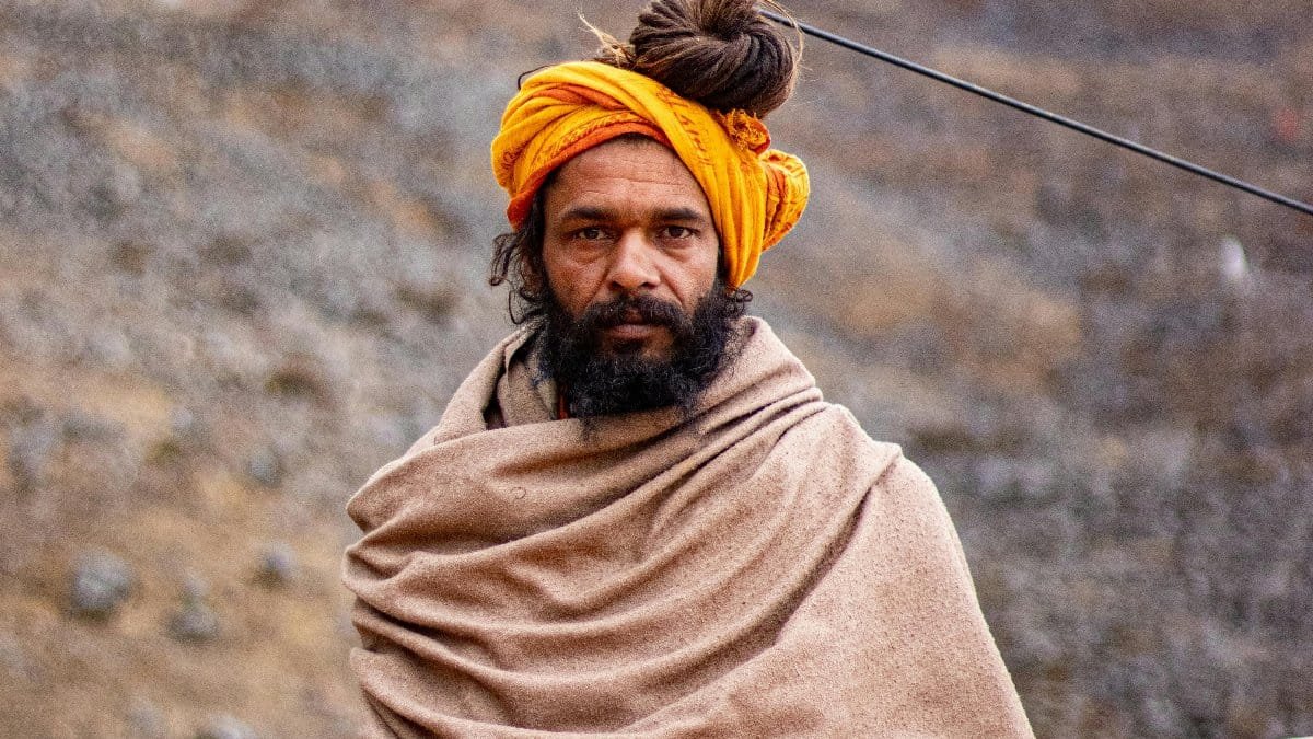 A spiritual man with a colorful turban sits in the Himalayas, surrounded by nature. via Pexels