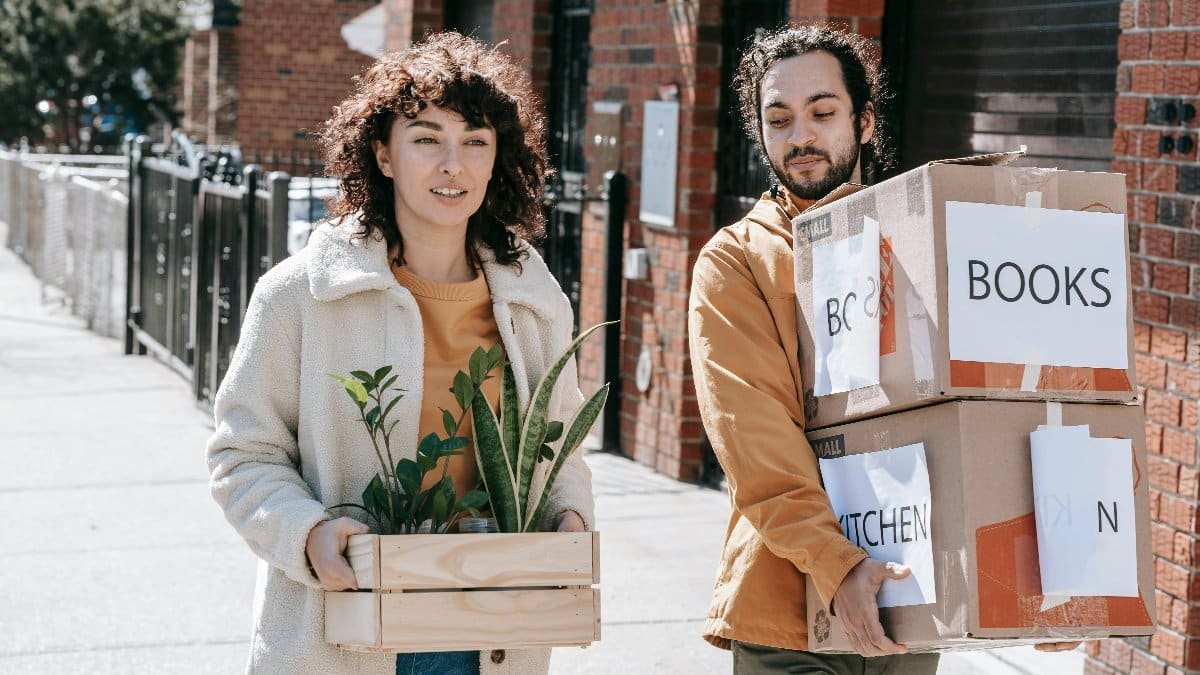 Young couple happily moving into their urban apartment with boxes and plants in daylight. via Pexels