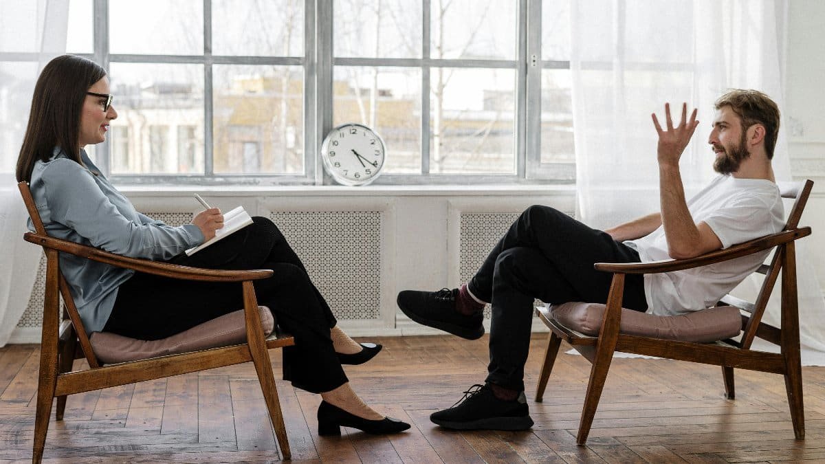 A therapist engaging in a counseling session with a male patient to support mental health. via Pexels