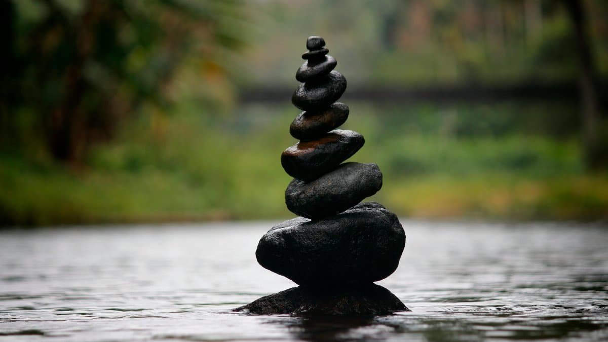 Balanced stones in a serene river evoke a sense of peace and tranquility.