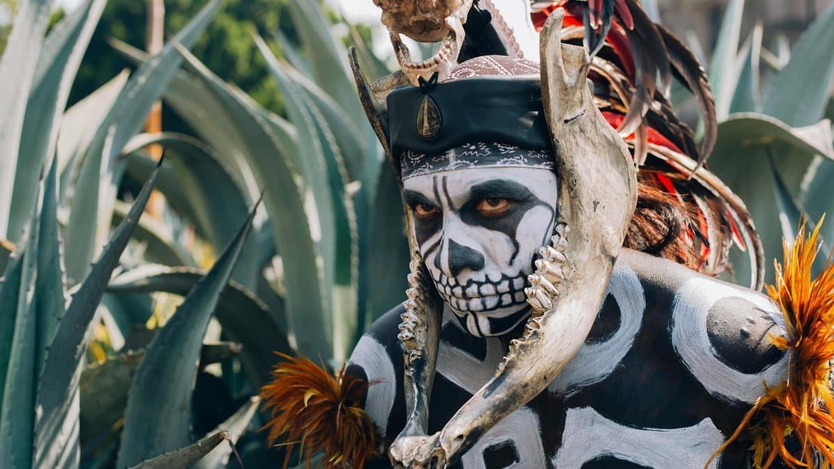A vivid portrayal of Mexican festival attire with intricate skull face paint and traditional headdress.
