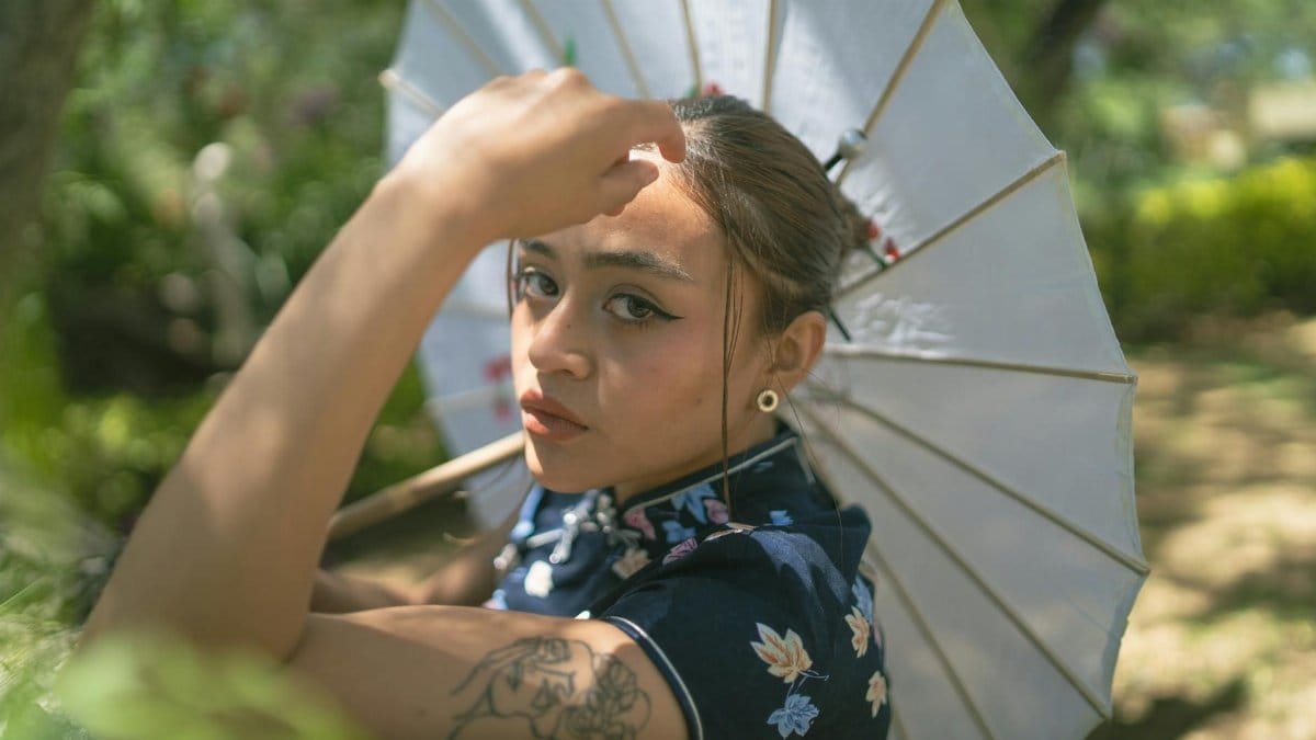 Captivating portrait of a woman outdoors holding a parasol, expressing grace and style.