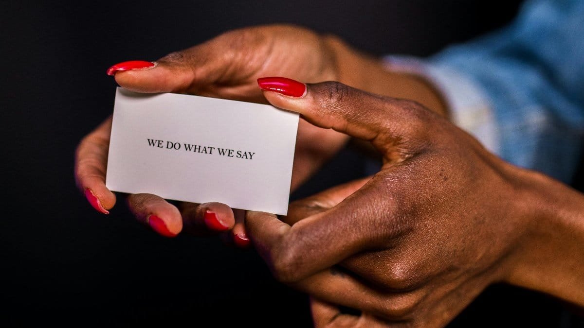 Close-up of a woman's hands holding a motivational card with 'we do what we say'. via Pexels
