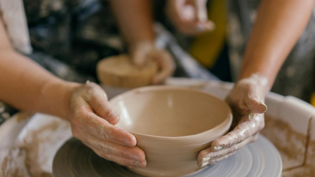 Hands shaping pottery on a spinning wheel, illustrating the art of crafting handmade clay items.