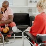 A man expresses emotions during a therapy session with a therapist in a modern office setting. via Pexels