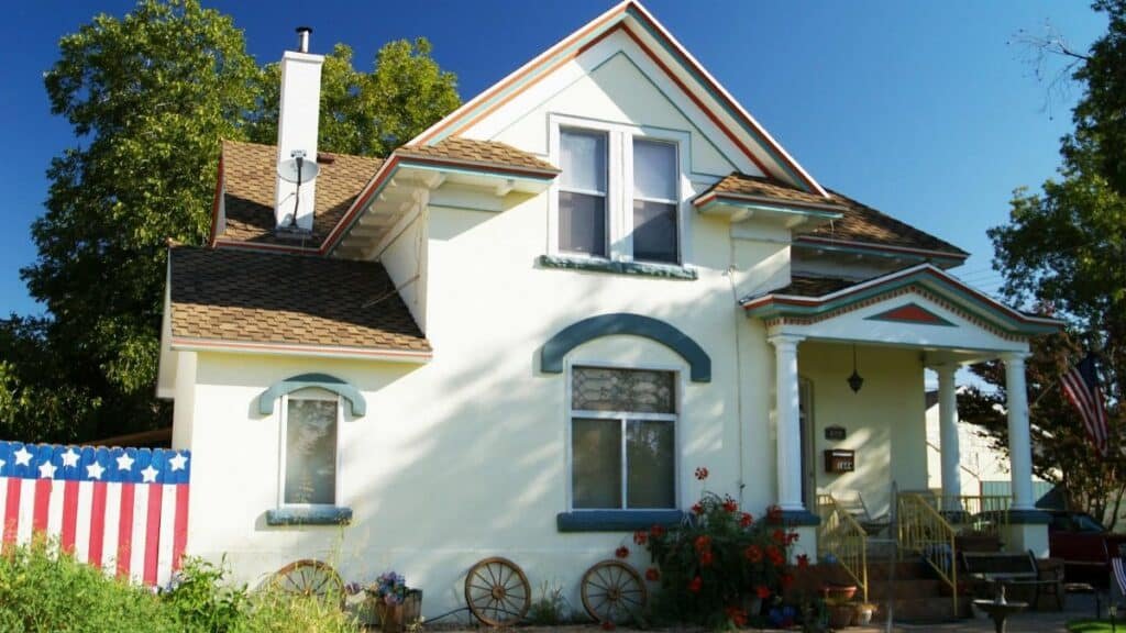 A picturesque suburban American house with a front yard and patriotic decorations.