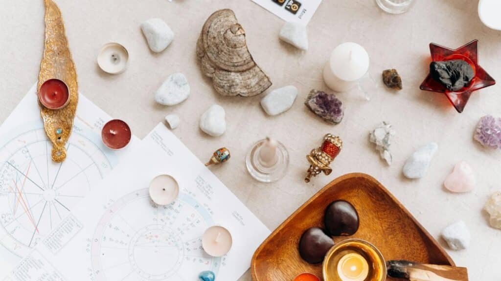 Flat lay of spiritual items including candles, crystals, and astrology charts for meditation.