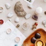 Flat lay of spiritual items including candles, crystals, and astrology charts for meditation.