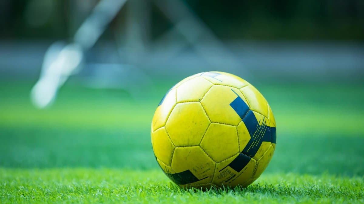 Close-up of a yellow soccer ball on a green field, perfect for sports and recreation themes.