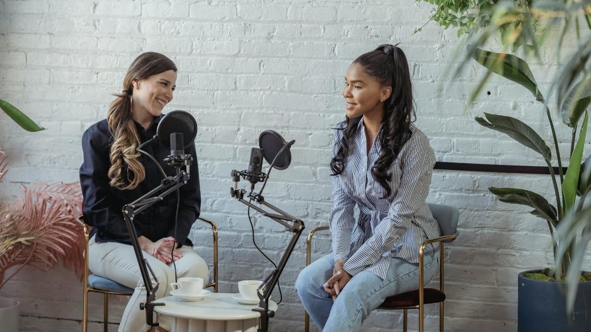 Diverse women communicating while recording voice in studio with white brick walls in daytime