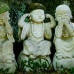 Three wise Buddha statues with moss detail in a peaceful Japanese garden.