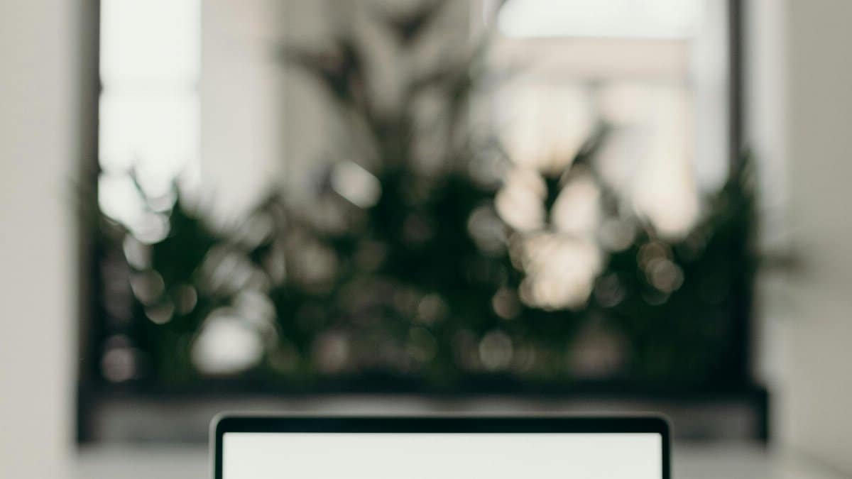 A minimalist workspace featuring an open laptop in a bright, serene indoor setting.