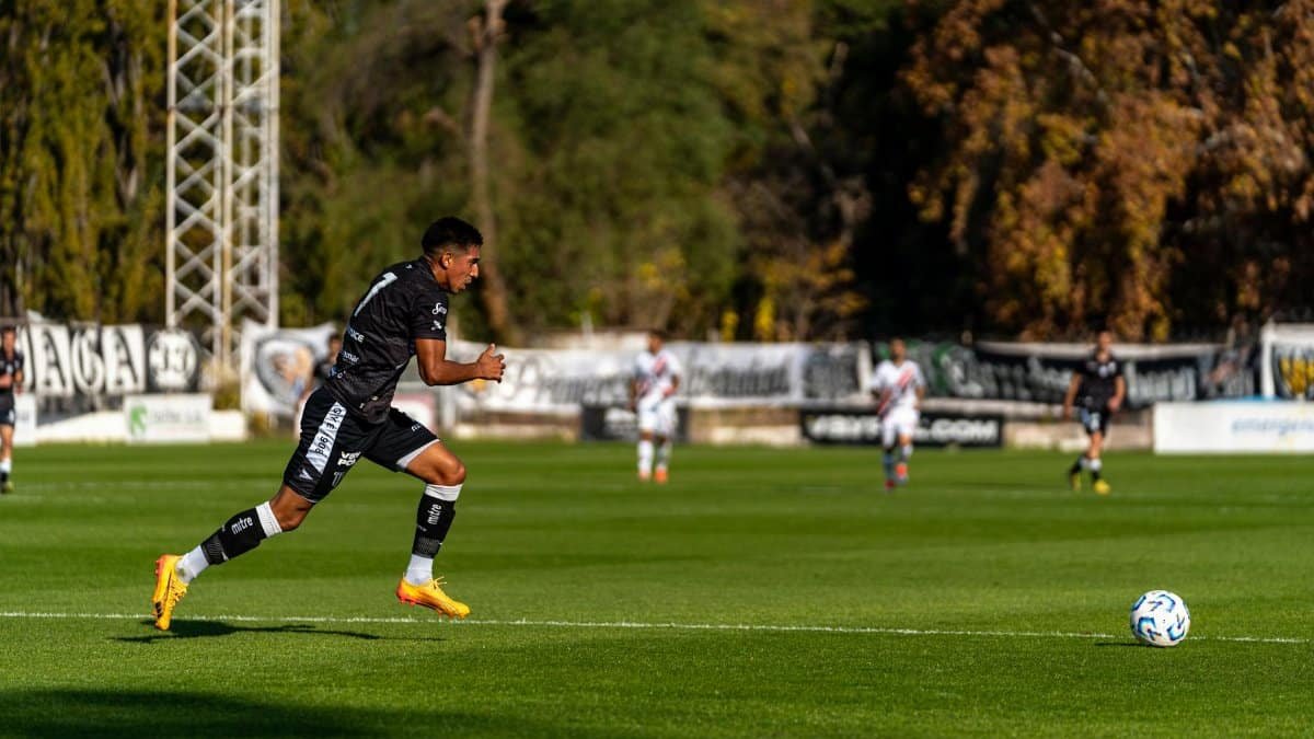 Soccer player sprints towards the ball on a sunny day match.