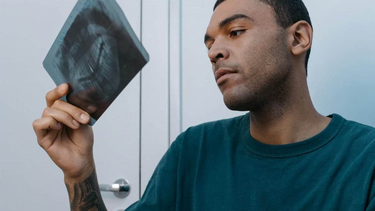 A man closely examines a dental x-ray, focusing on his dental care.