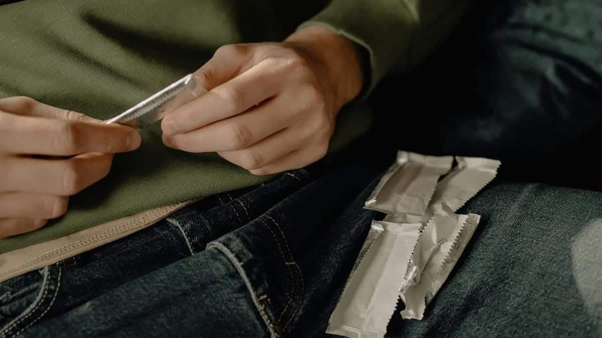 A young man relaxing at home, unwrapping chewing gum while resting on a sofa.