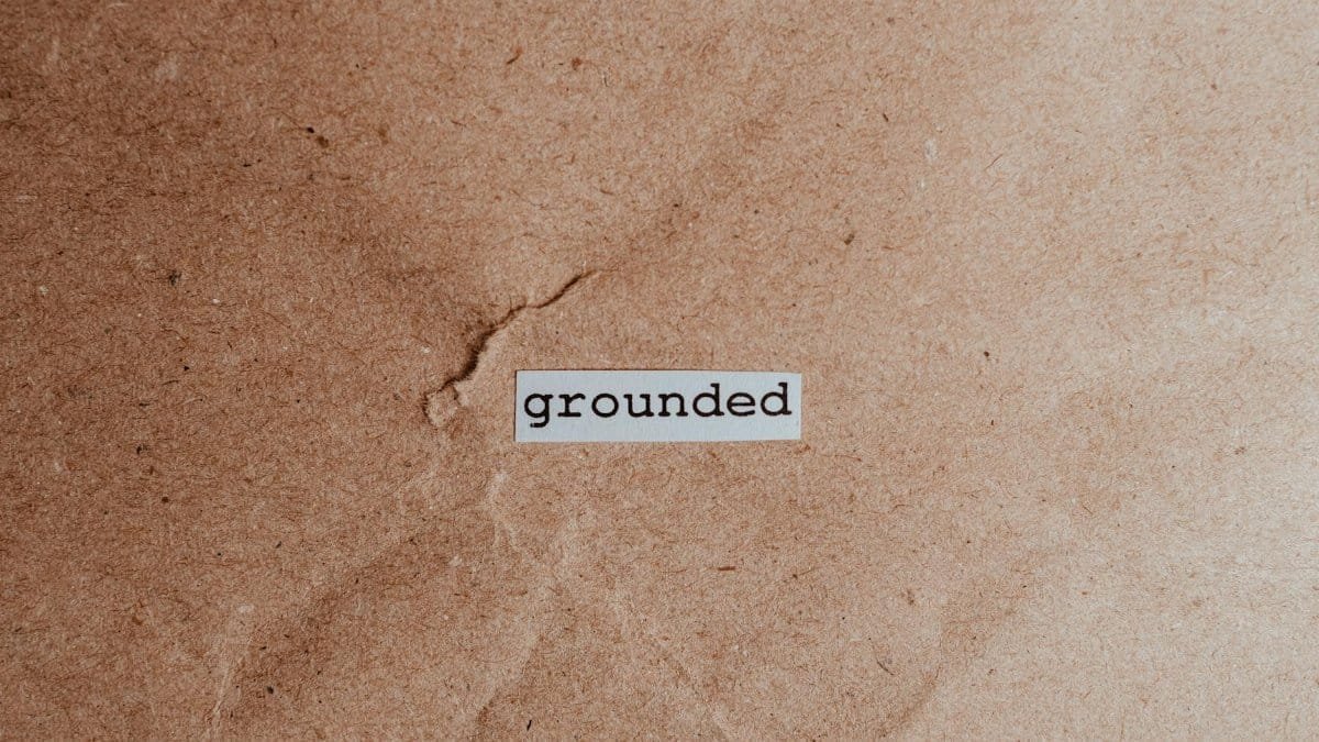 Textured brown surface with the word 'grounded', conveying stability and mindfulness.