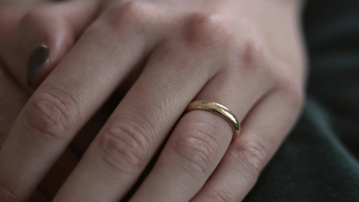 Elegant close-up of a hand wearing a gold ring, capturing intricate details of skin texture.