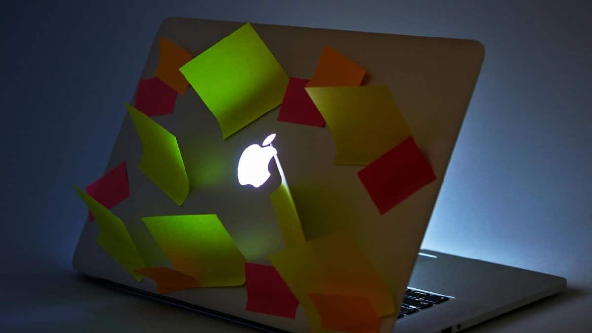 A glowing laptop with sticky notes attached, highlighting busy workspace or reminders.
